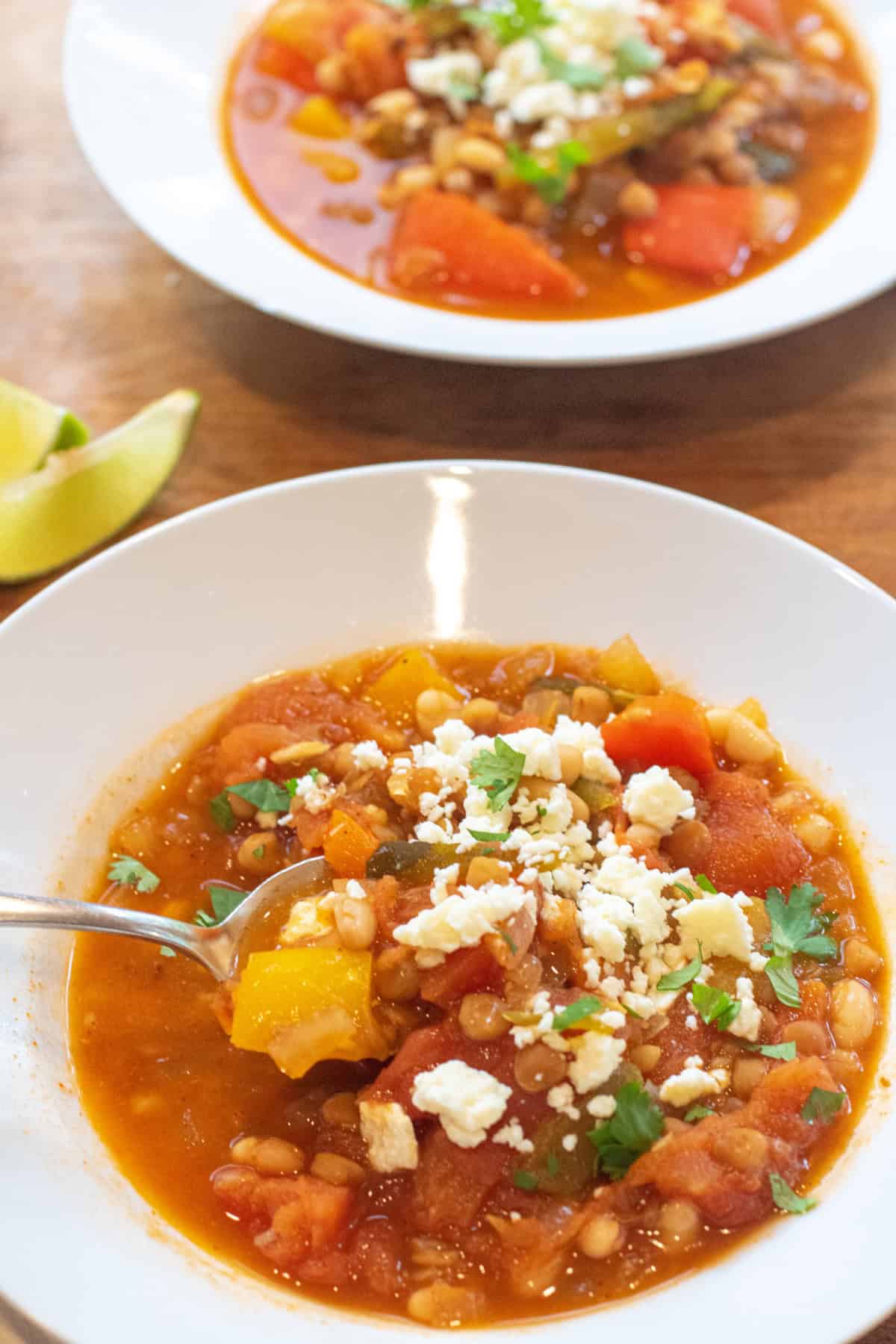 a bowl of lentil pepper stew topped with cotija cheese and cilantro.
