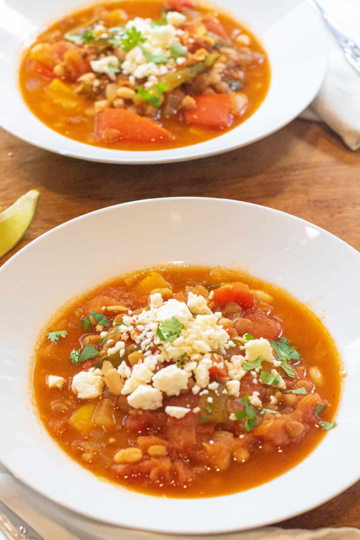 a bowl of lentil pepper stew topped with cotija cheese and cilantro.