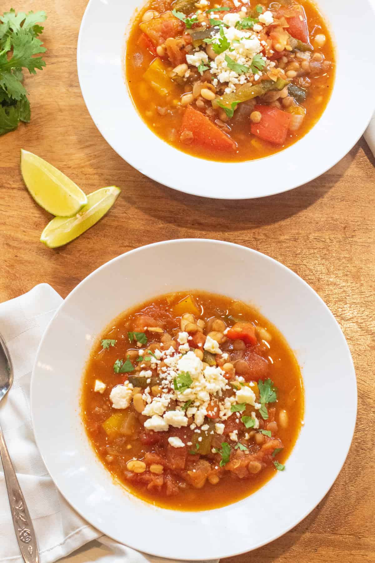 a bowl of lentil pepper stew topped with cotija cheese and cilantro.