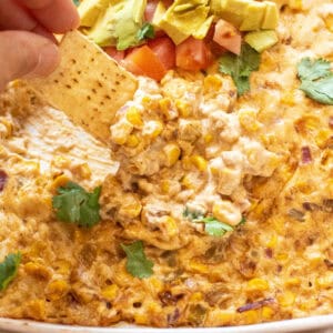 a chip dipping into cheesy corn dip.