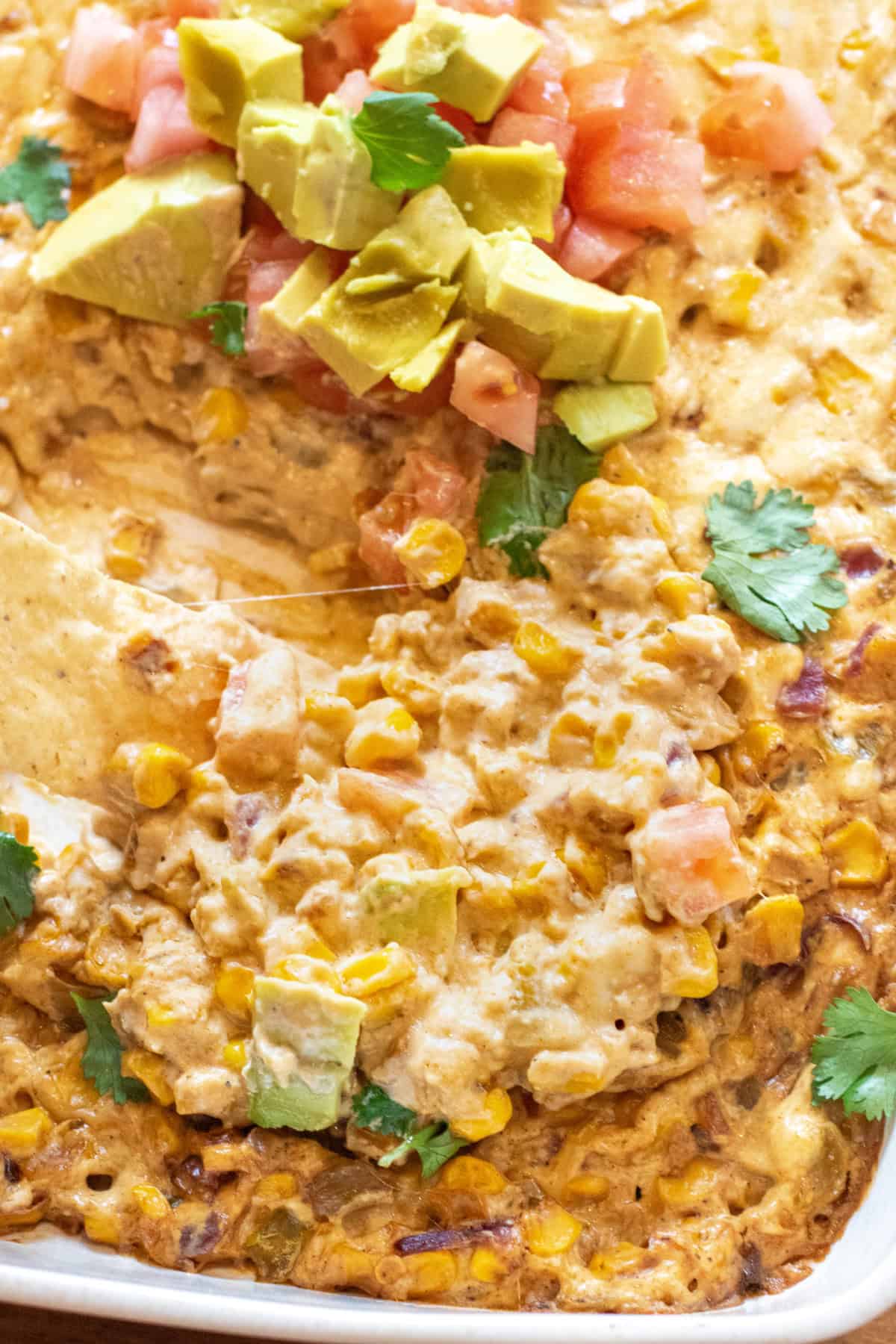 a chip dipping into cheesy corn dip.