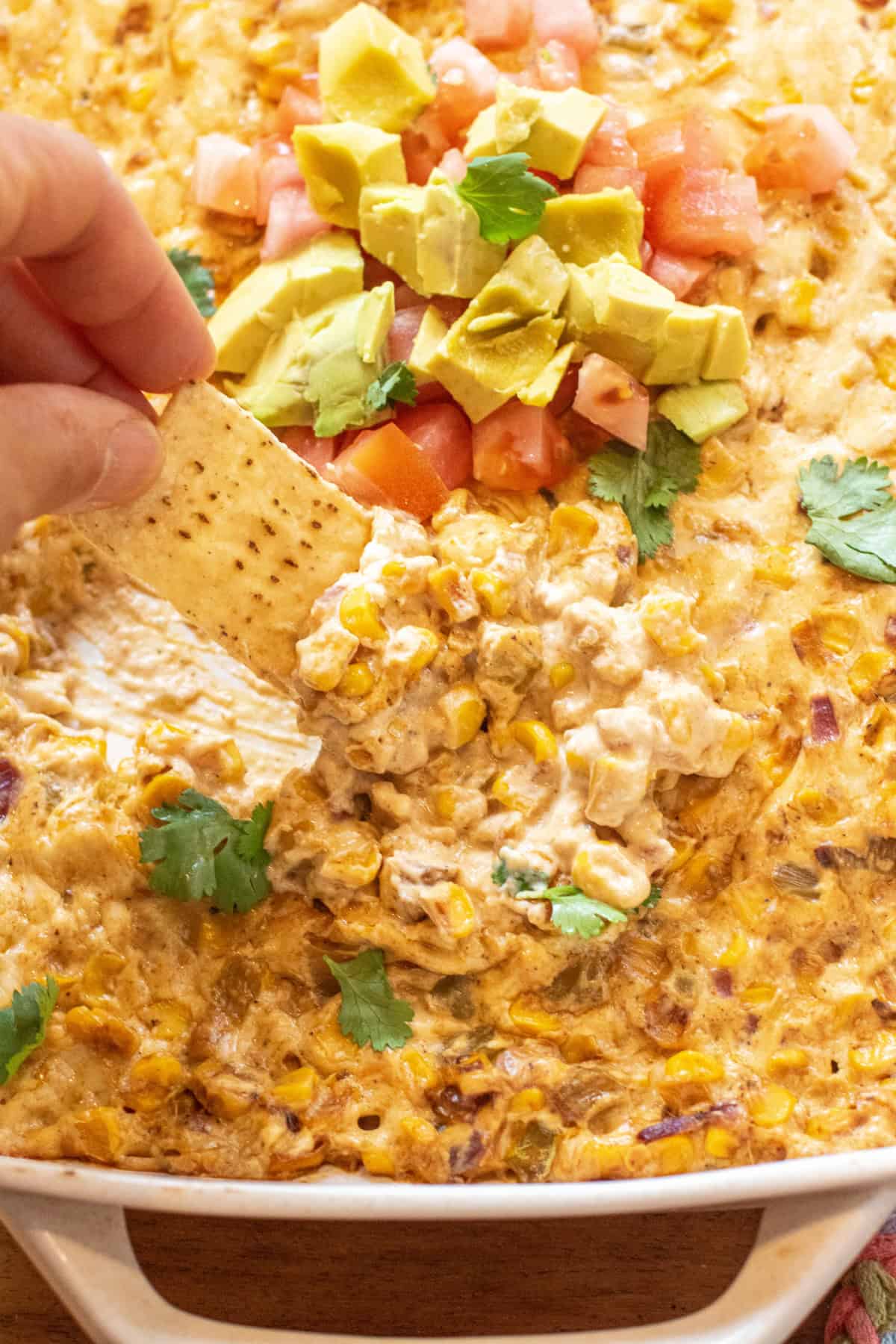 a chip dipping into cheesy corn dip.