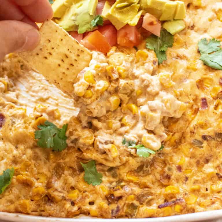 a chip dipping into cheesy corn dip.
