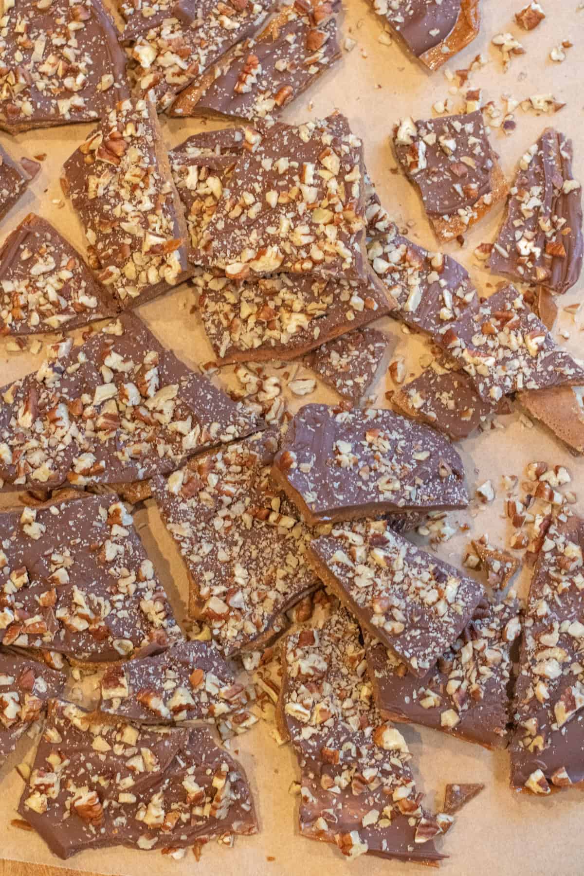 an overhead of a bunch of pecan covered toffee all broken up.