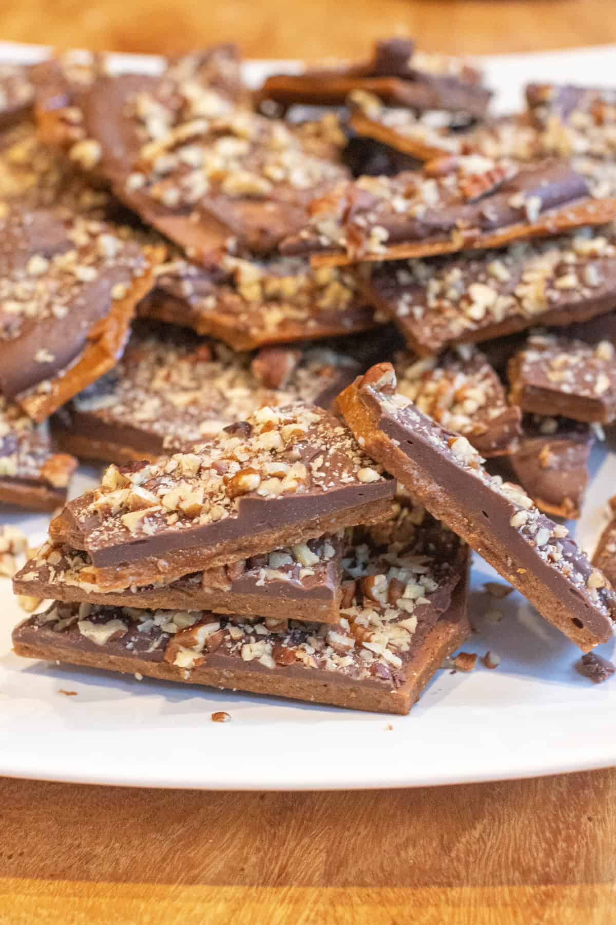 a plate of toffee with chocolate and pecans.