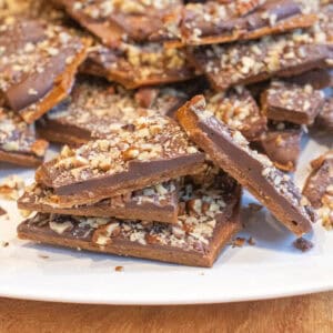 a plate of toffee with chocolate and pecans.