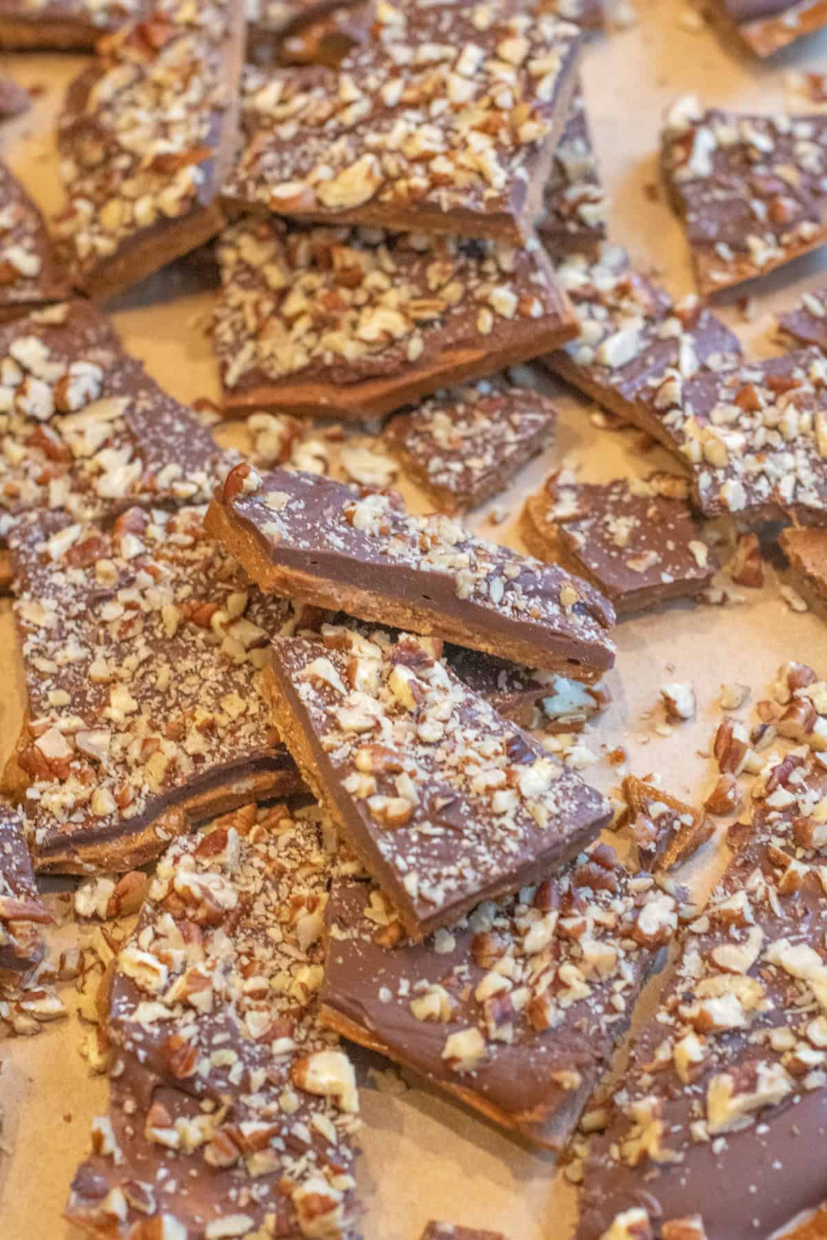 an overhead of a bunch of pecan covered toffee all broken up.