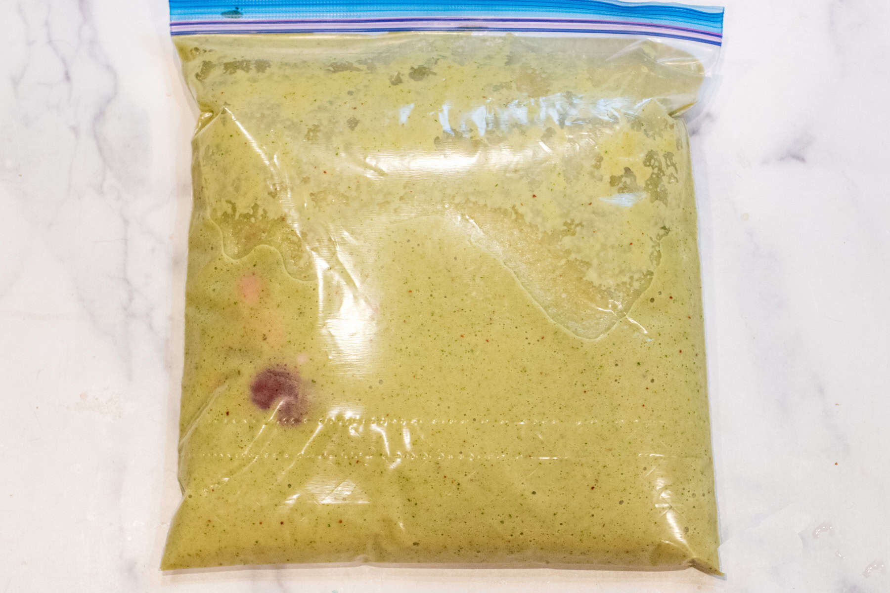 a plastic bag with marinade and flank steak inside.