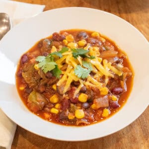 a bowl of vegetarian chili with shredded cheese and cilantro on top.