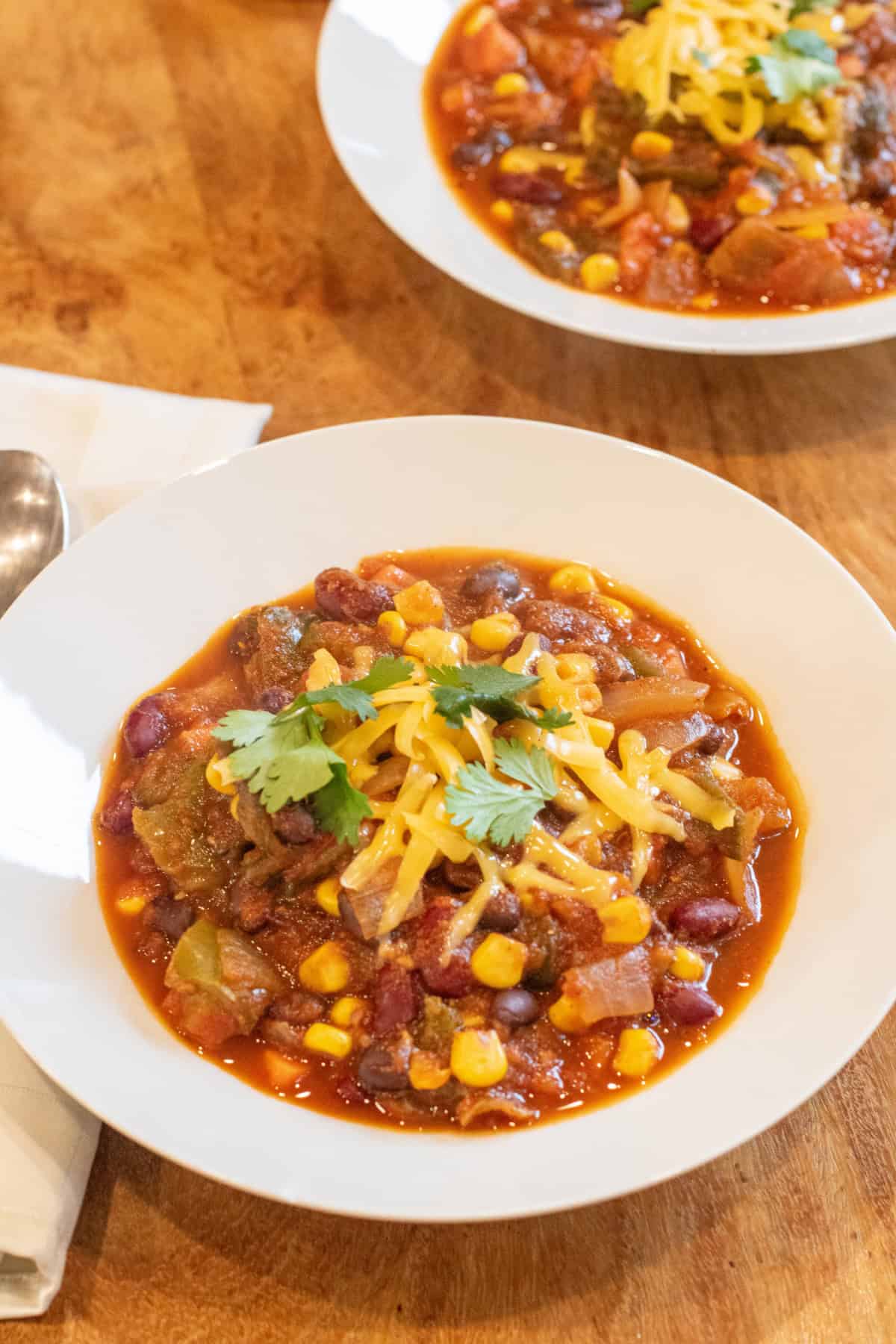 two bowls of chili with shredded cheese and fresh cilantro.