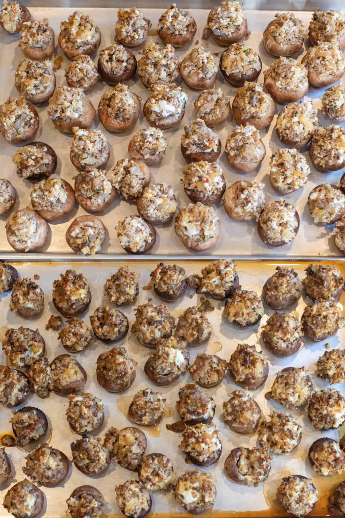 two trays, one filling with uncooked stuffed mushrooms over a tray of baked stuffed mushrooms.