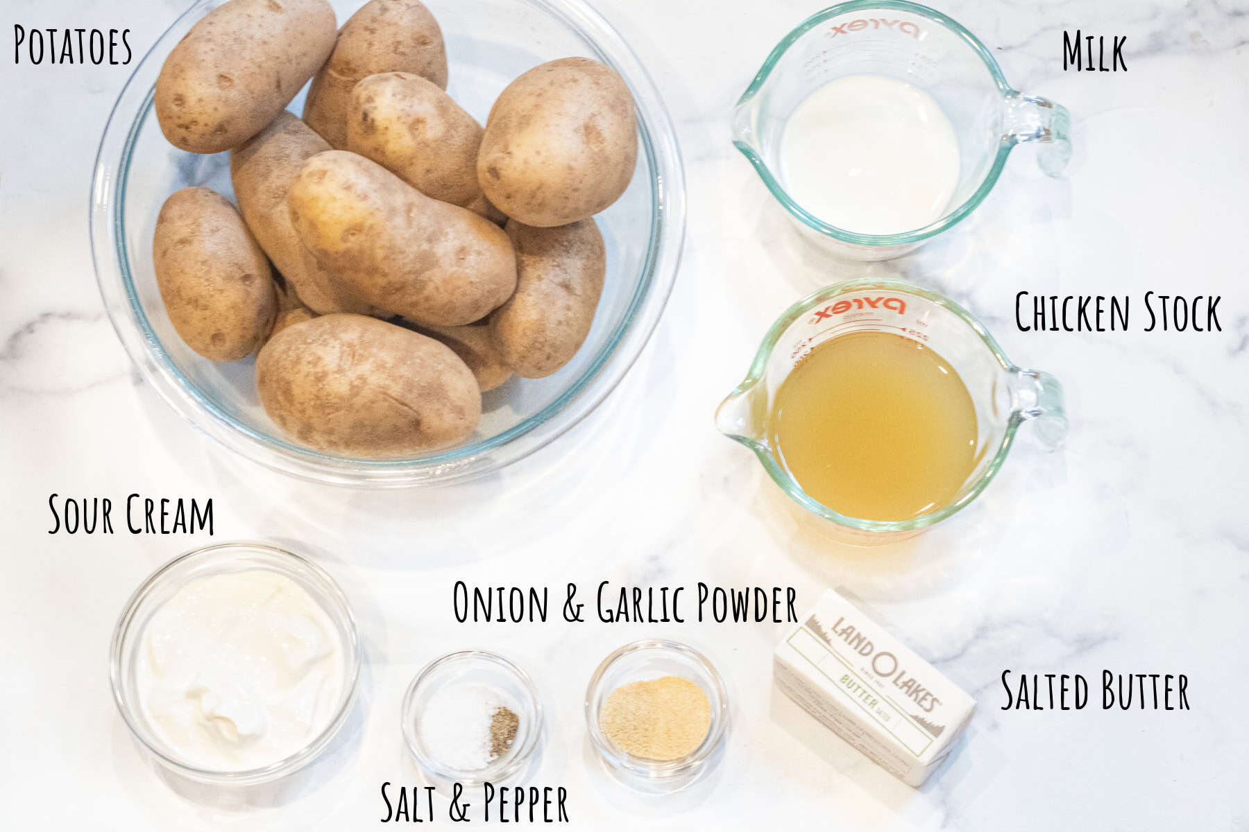 a bowl of potatoes, pyrex of stock, milk, and bowls of sour cream, salt and pepper, and onion and garlic powder and butter all labeled.