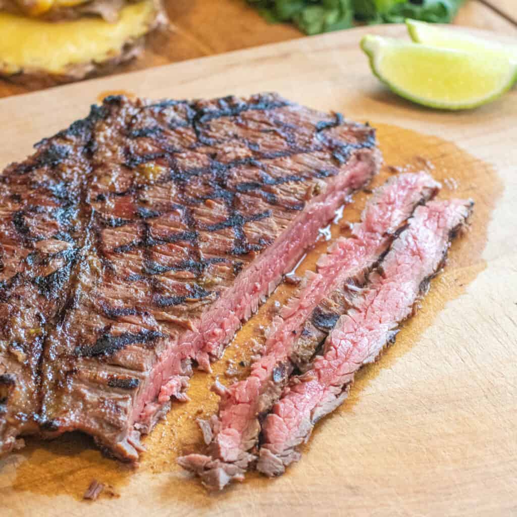 a grilled sliced flank steak on a cutting board.