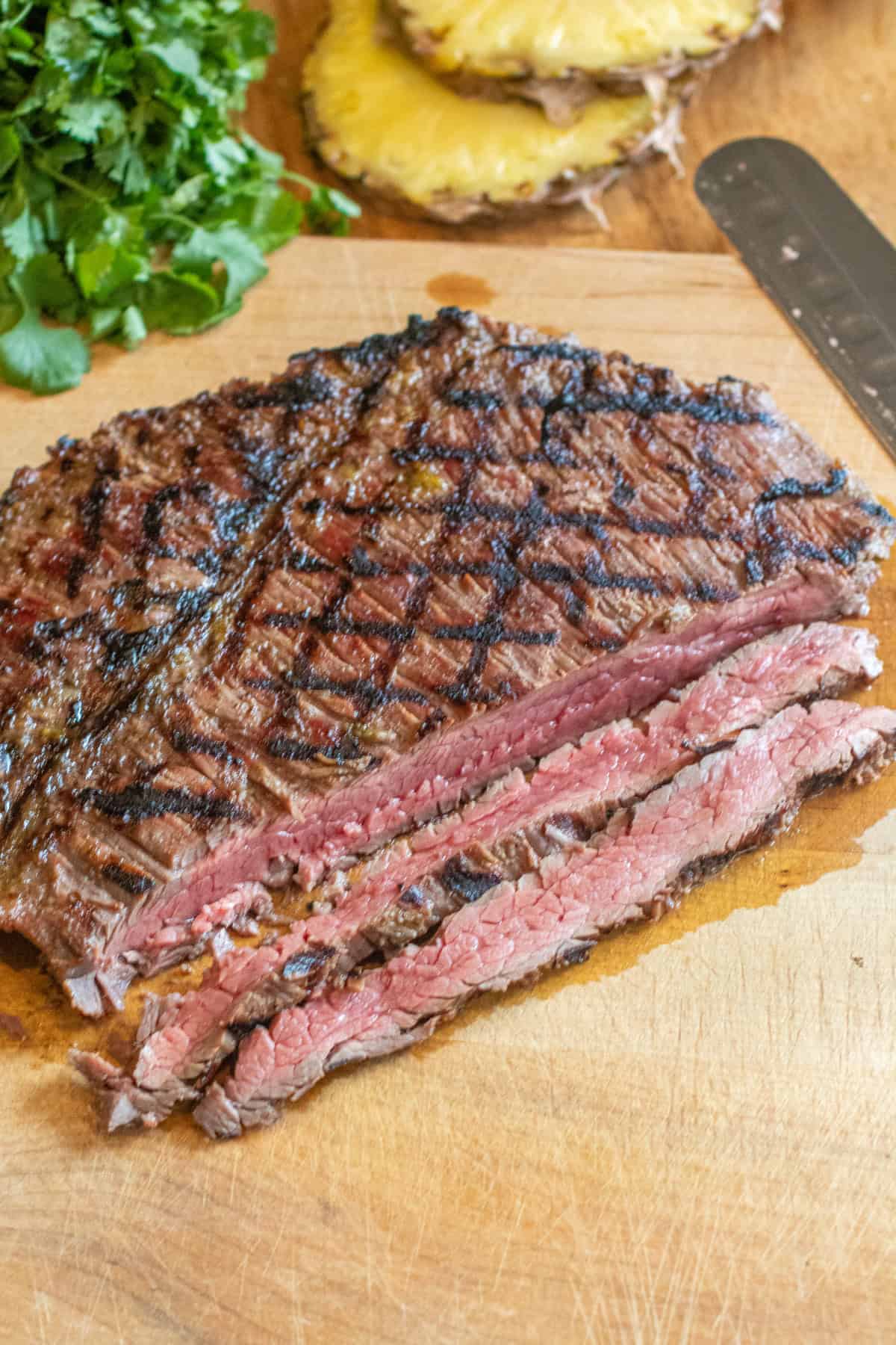 a grilled sliced flank steak on a cutting board.