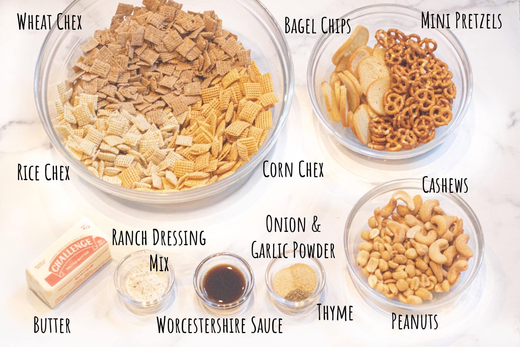 a bowl of different chex cereal, peanuts, pretzels, bagel chips, spices, and butter all labeled.