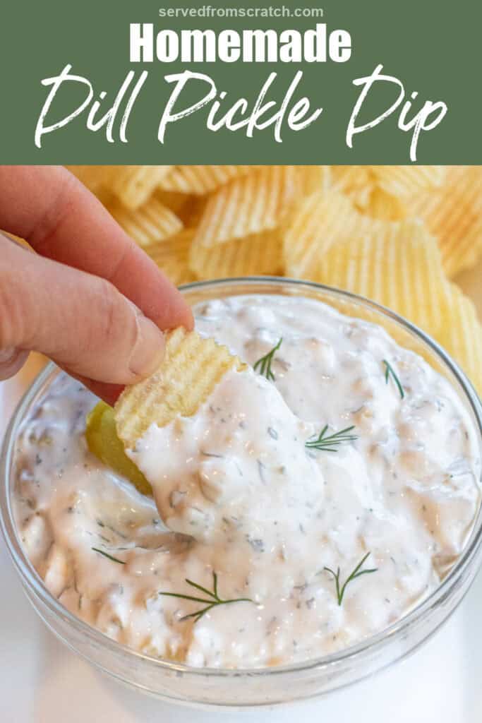 a bowl of creamy dip with a pickle and fresh dill on a plate of chips and a hand holding a chip with dip with Pinterest pin text.