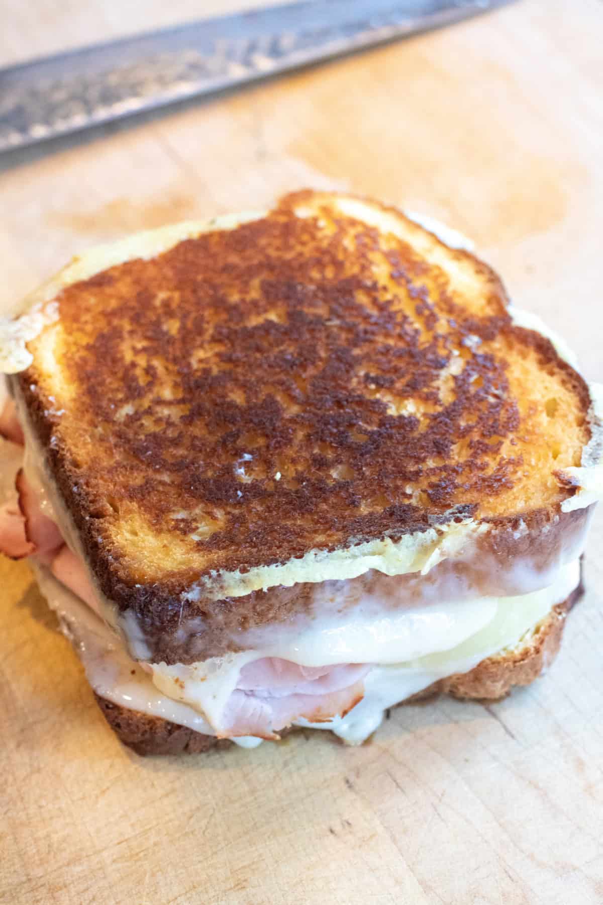 a crispy grilled cheese with ham and pineapple on a cutting board.
