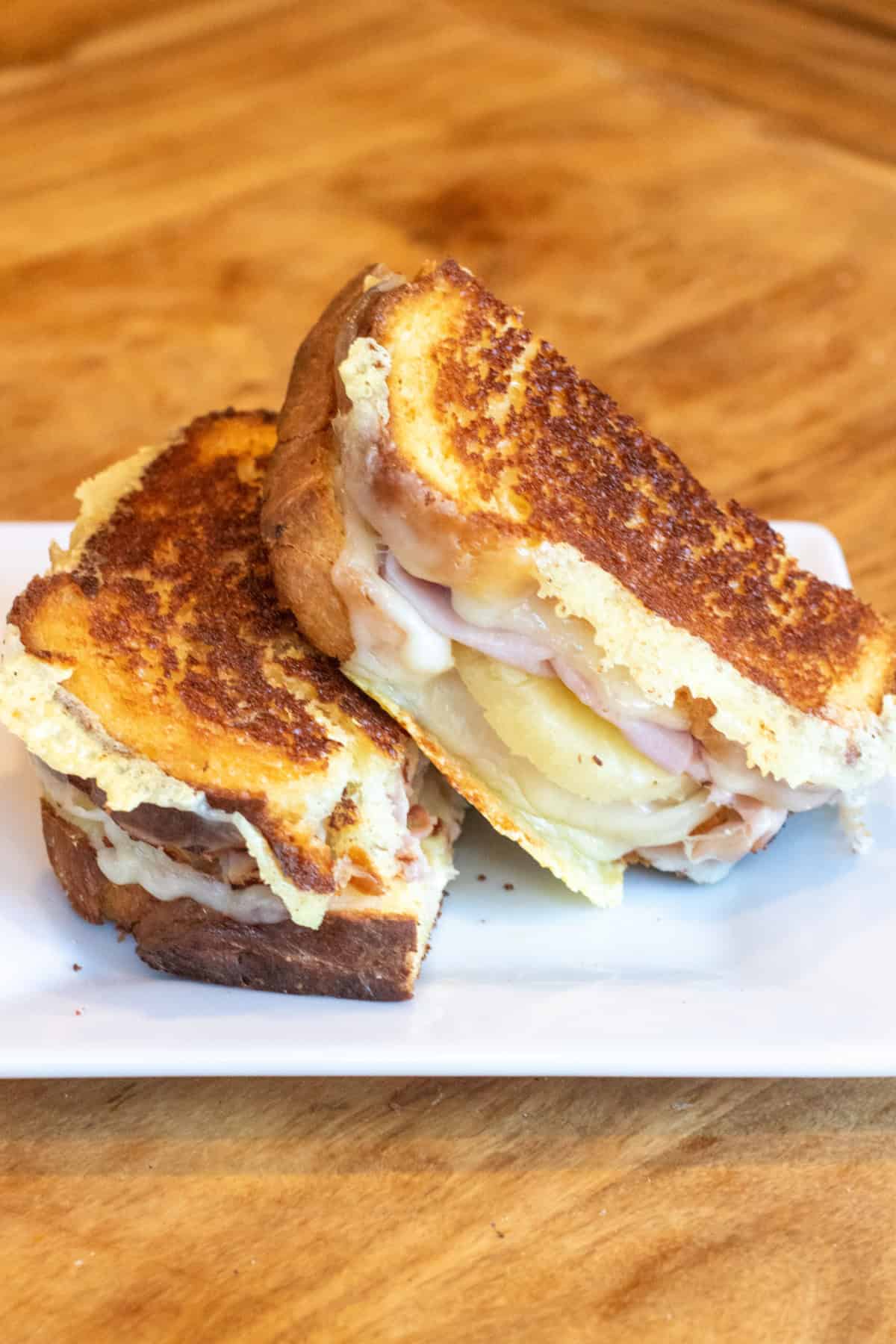 a halved grilled cheese with ham and pineapple stacked on a plate.