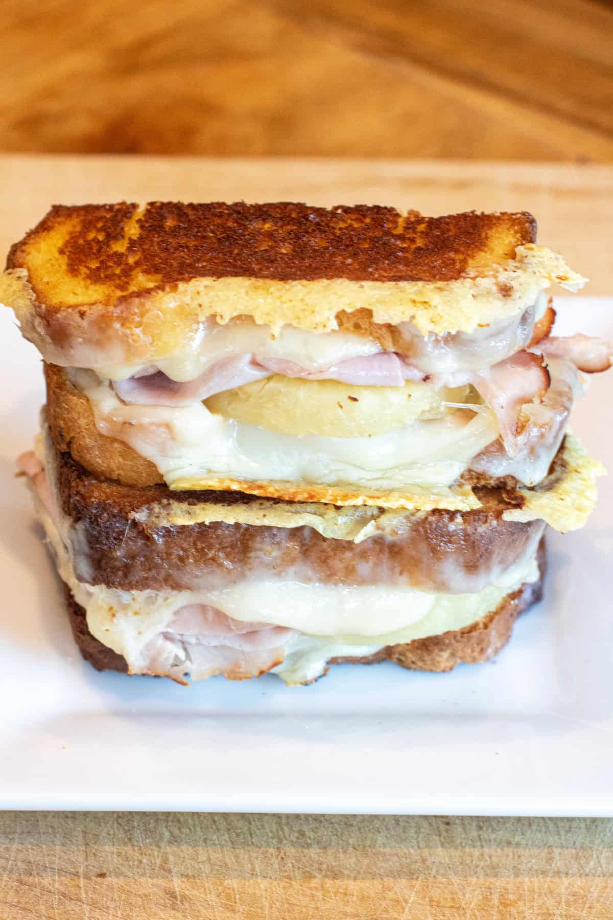 a halved grilled cheese with ham and pineapple stacked on a plate.