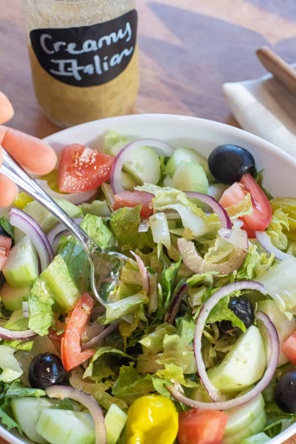 a big bowl of green salad with dressing and a fork in it.