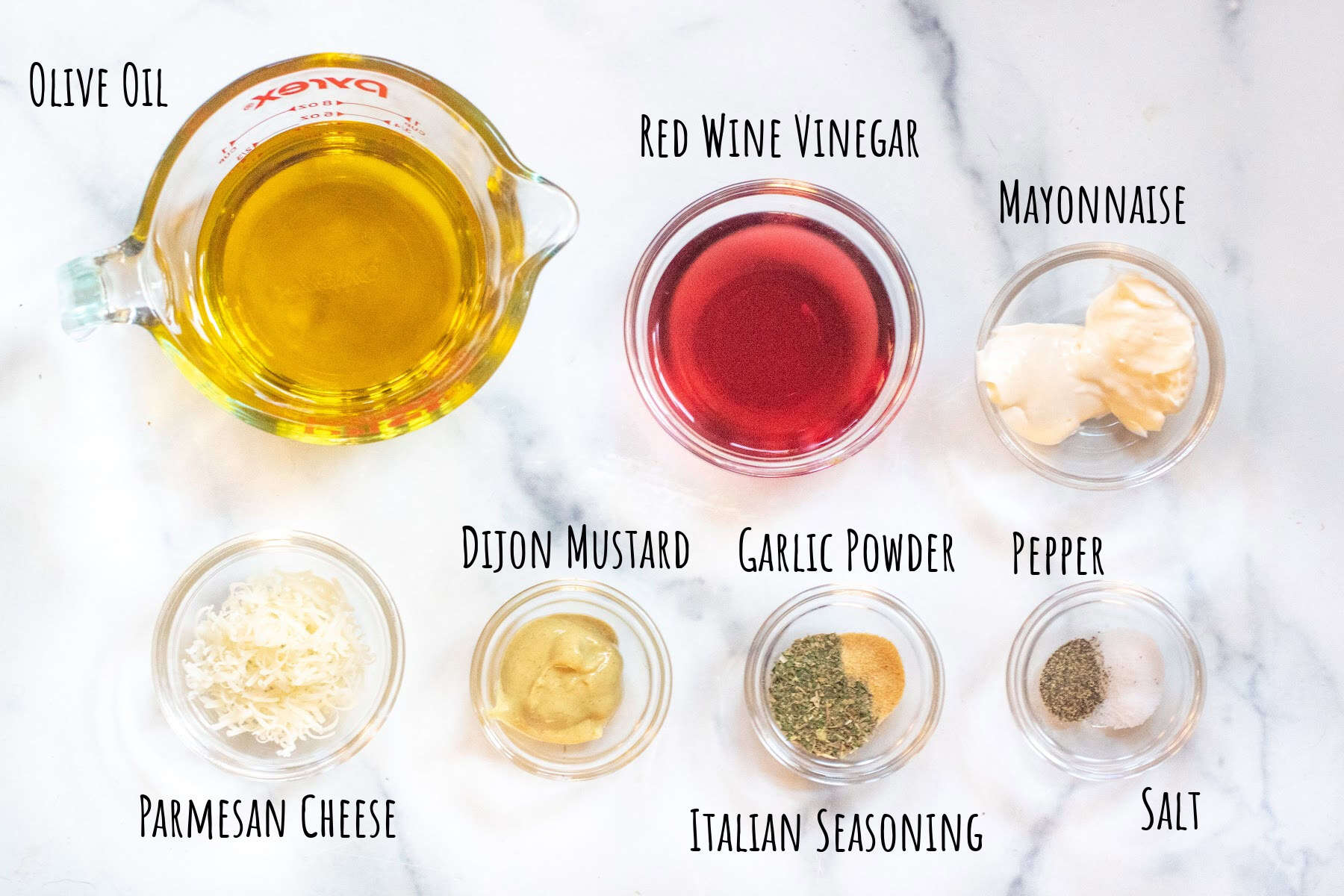 olive oil, red wine vinegar, mayo, parmesan cheese, dijon mustard, italian seasoning, garlic powder, salt, and pepper in bowls and labeled.
