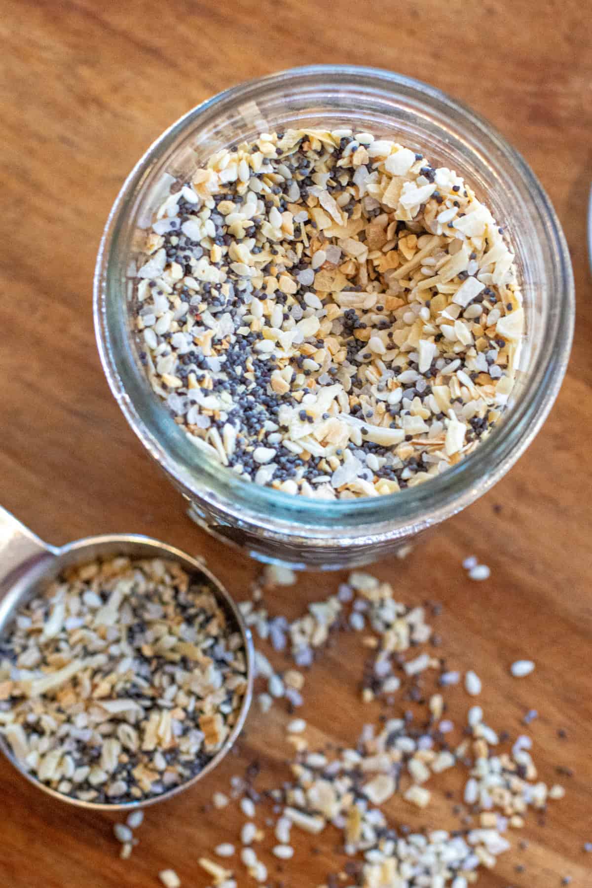 an overhead of a jar of everything bagel seasoning and a tablespoon with some in it.