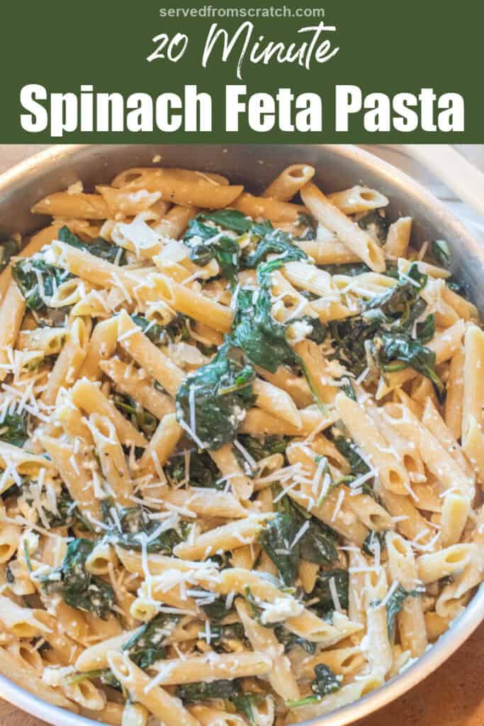 an overhead of a pan of spinach in penne pasta and shredded cheese with Pinterest pin text.