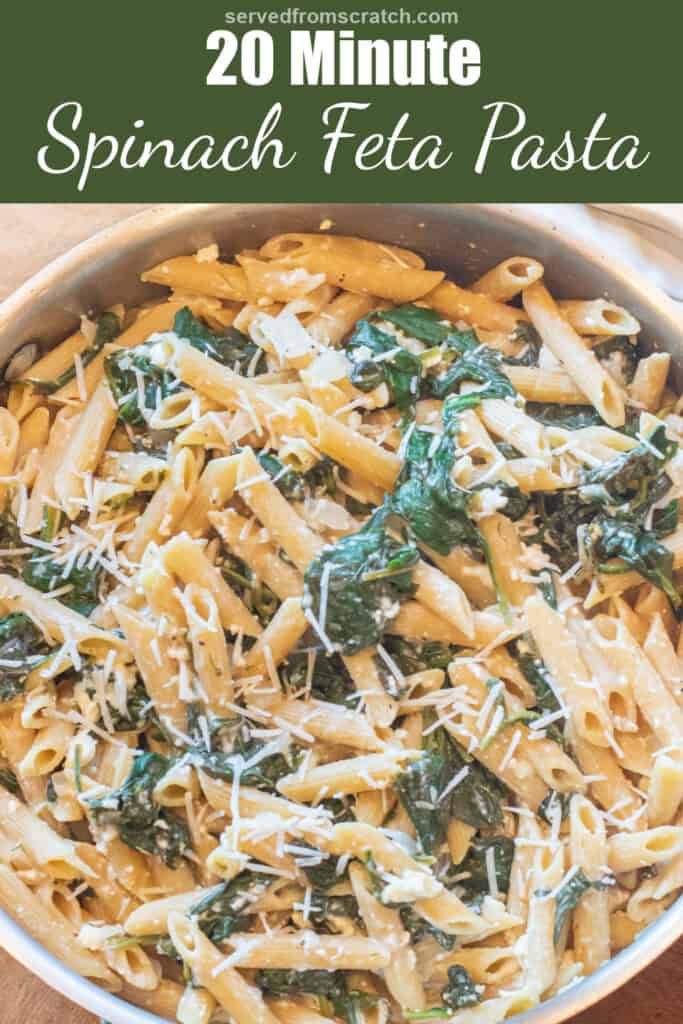an overhead of a pan of spinach in penne pasta and shredded cheese with Pinterest pin text.