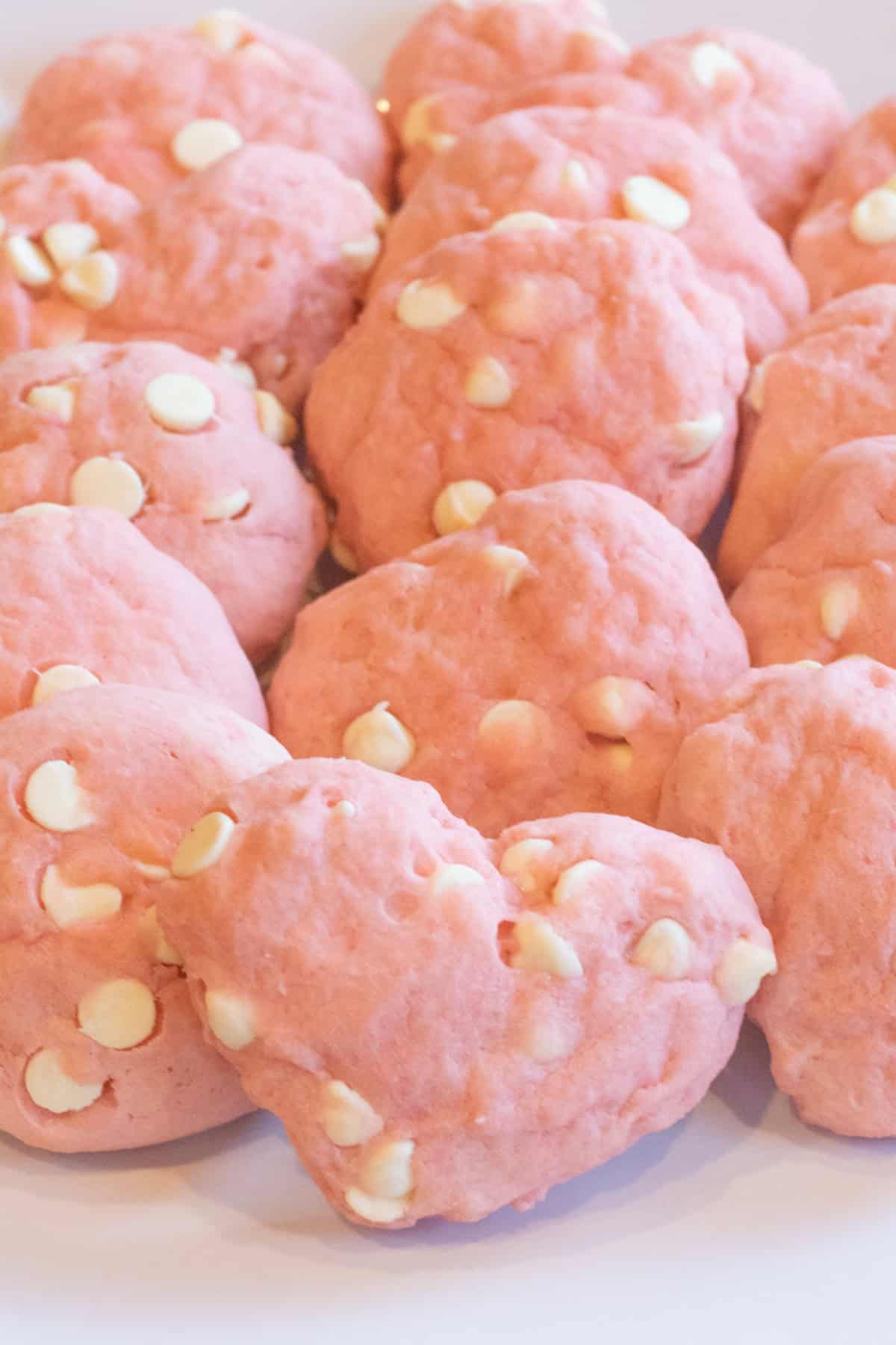 a plate of pink cookies, some heart shaped and with white chocolate chips.