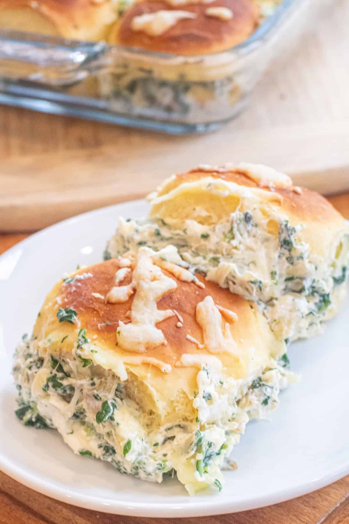 two spinach artichoke dip filled sliders on a plate.