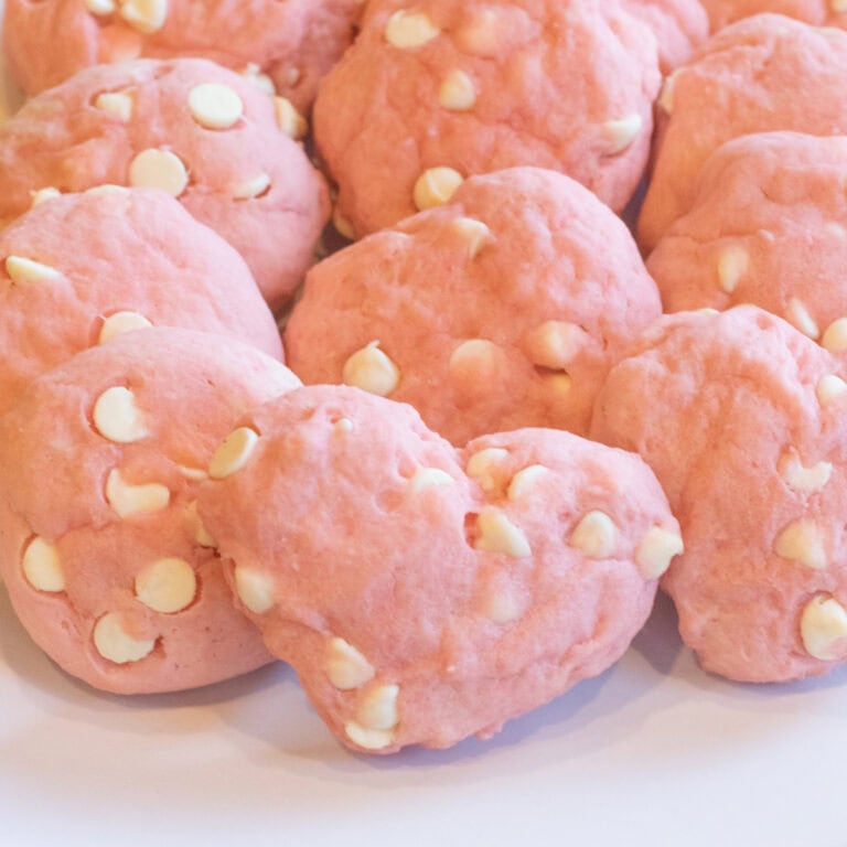 a plate of pink cookies with white chocolate chips on a plate.