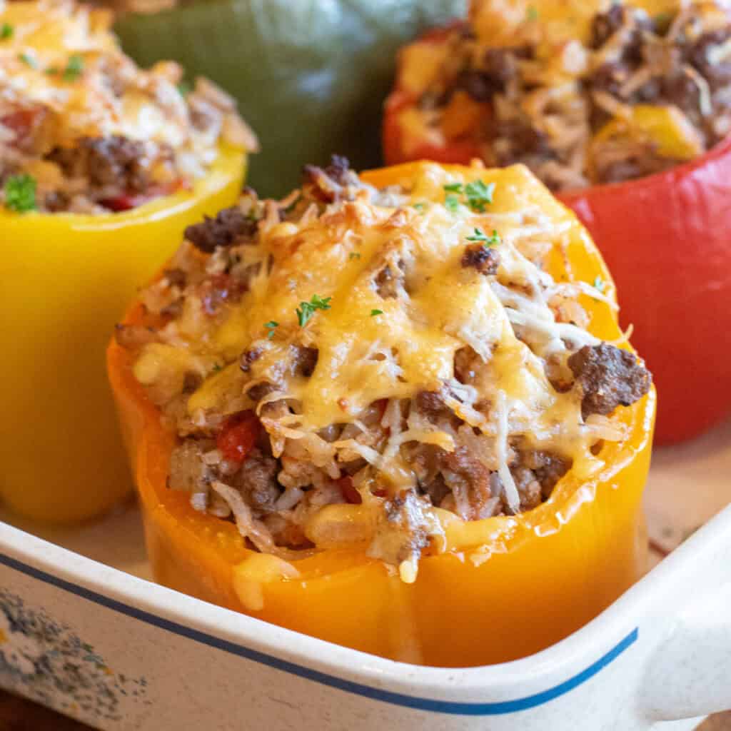 a close up of a orange stuffed pepper with ground beef, rice, and melted cheese.