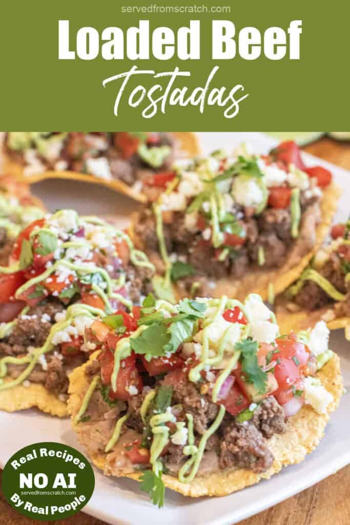a plate with loaded beef tostadas with beans, beef, pico, cotija, cilantro, and avocado cream sauce and Pinterest pin text with NO AI sticker.