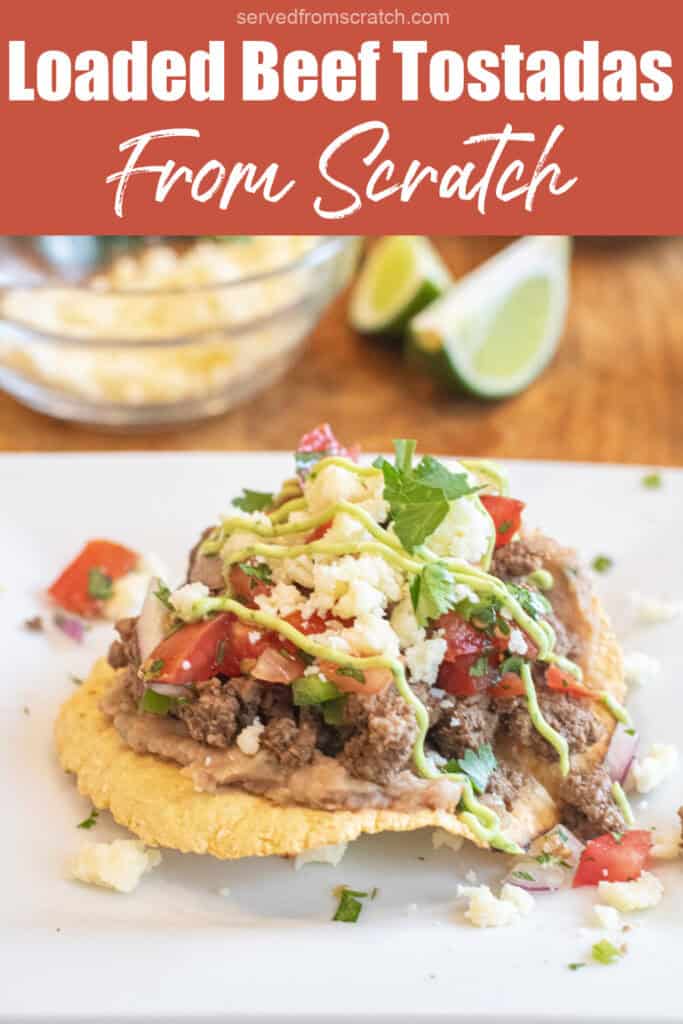 a loaded beef tostada on a plate with ground beef, cheese, pico, and a sauce, and Pinterest pin text.