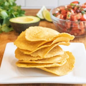 a plate of tostada shells in front of a bowl of pico and avocado, lime, and cilantro.