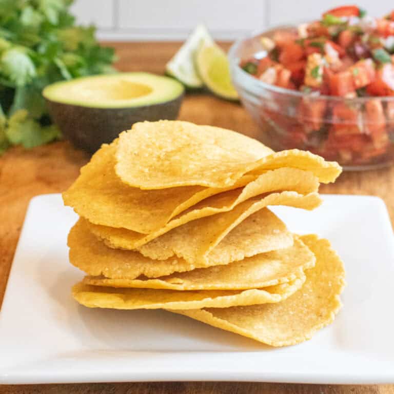 a plate of tostada shells in front of a bowl of pico and avocado, lime, and cilantro.