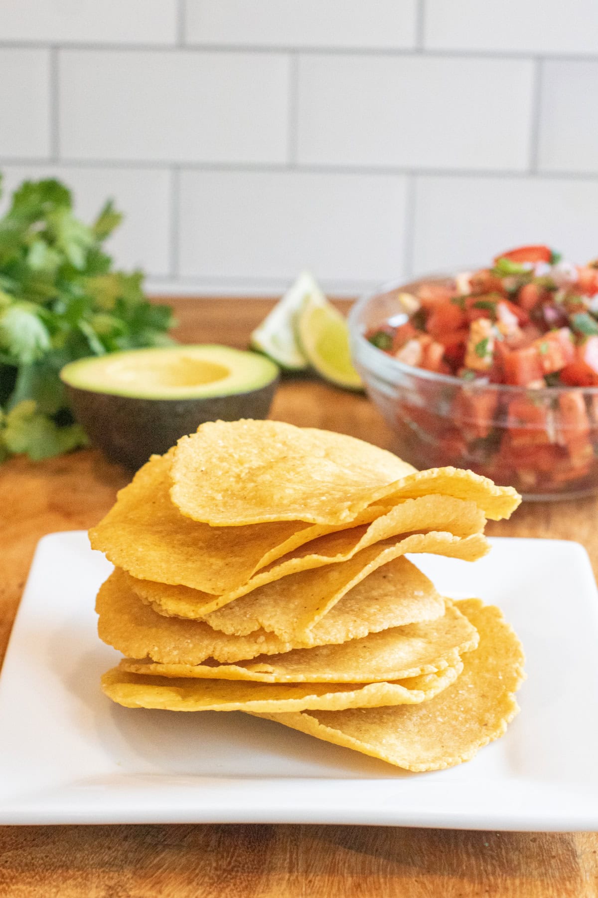a plate of tostada shells in front of a bowl of pico and avocado, lime, and cilantro.