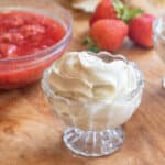 a small bowl of soft serve ice cream in front of strawberries and a bowl of compote.