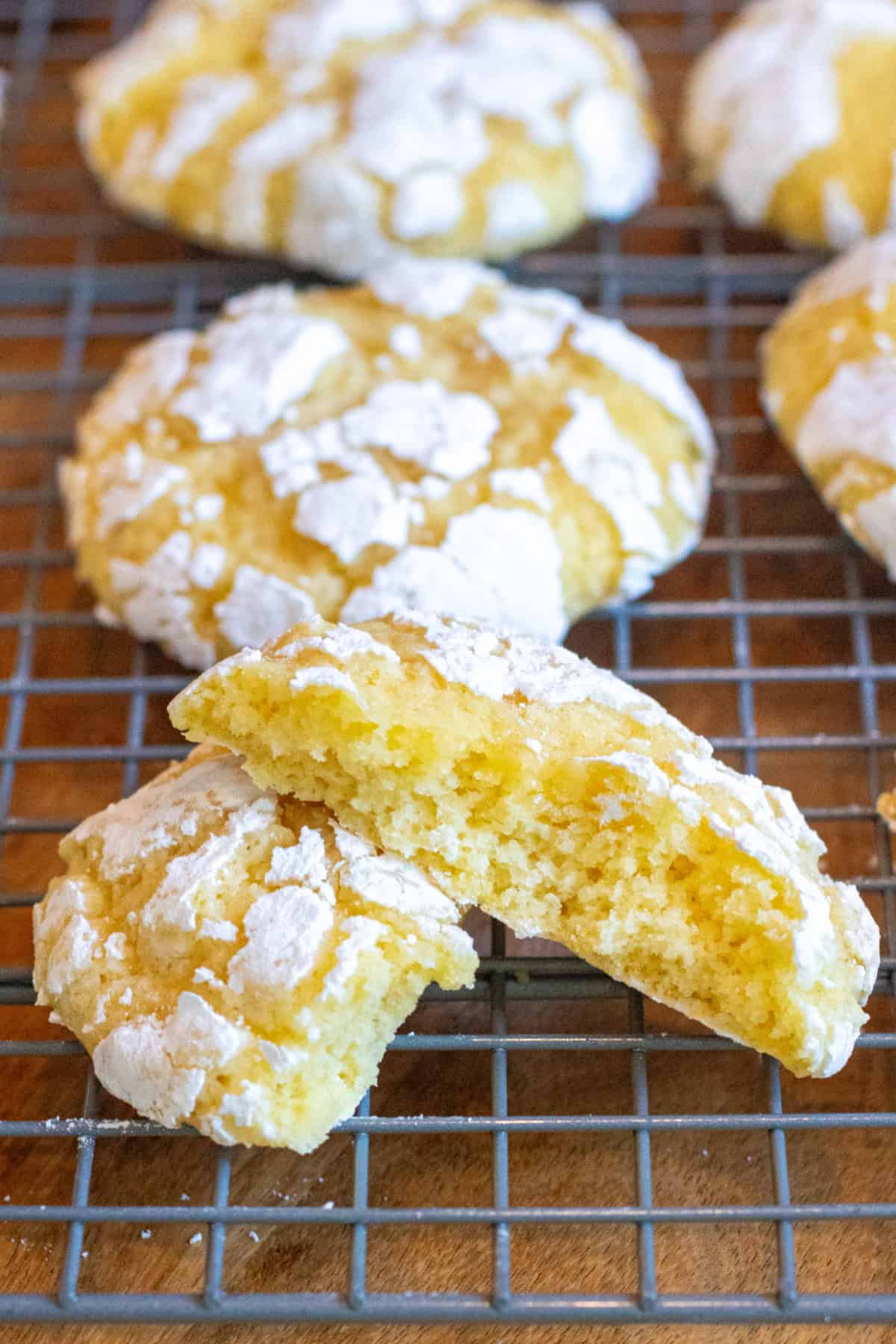 a tray of cookies with one lemon crinkle cookie halved and stacked.