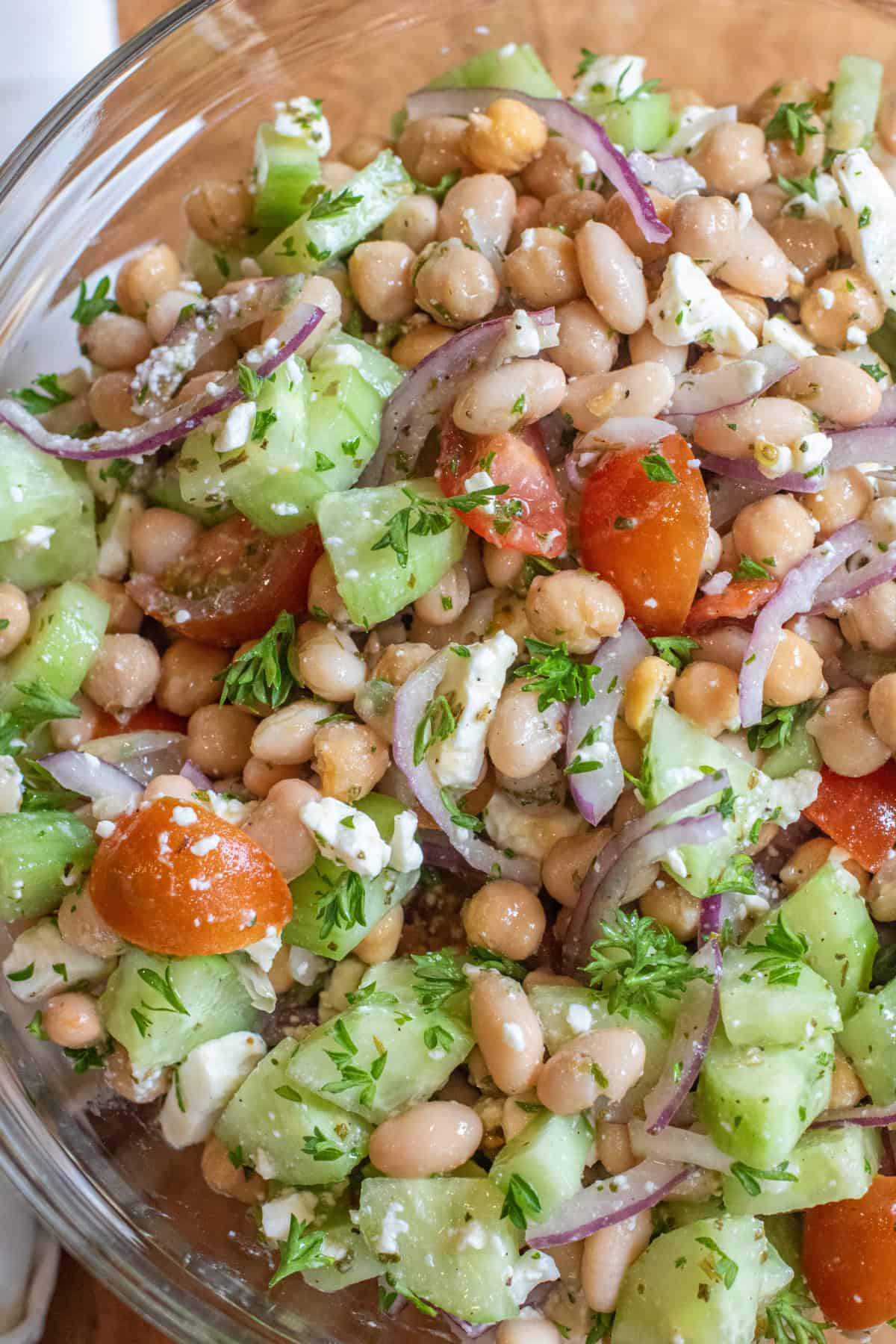 a bowl of chickpeas, beans, cucumber, tomatoes, onions, and feta.