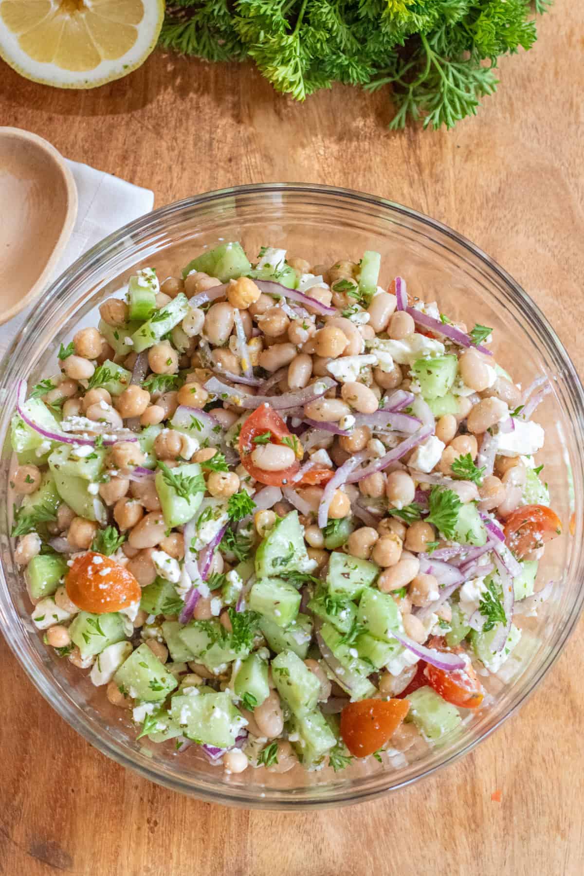 a bowl of chickpeas, beans, cucumber, tomatoes, onions, and feta
