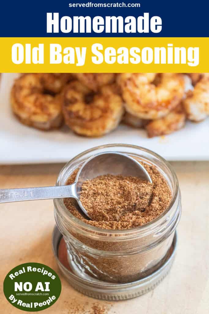 a small mason jar with a spoon and a seasoning mix in front of a plate of cooked seasoned shrimp with Pinterest pin text and no AI Sticker.