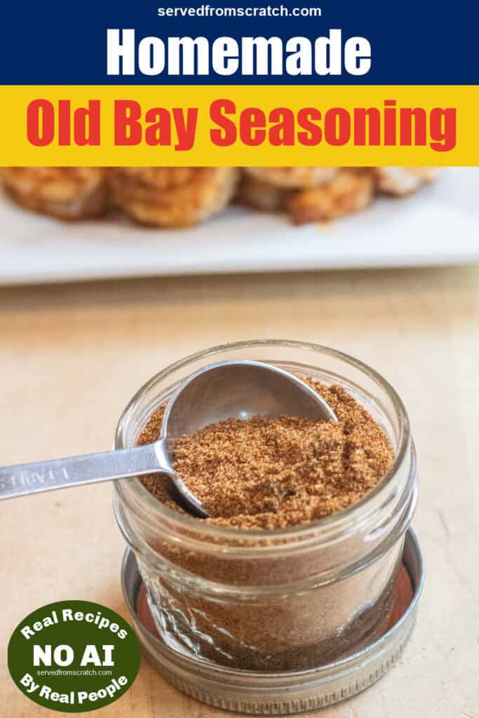 a small mason jar with a spoon and a seasoning mix in front of a plate of cooked seasoned shrimp with Pinterest pin text and no AI Sticker.