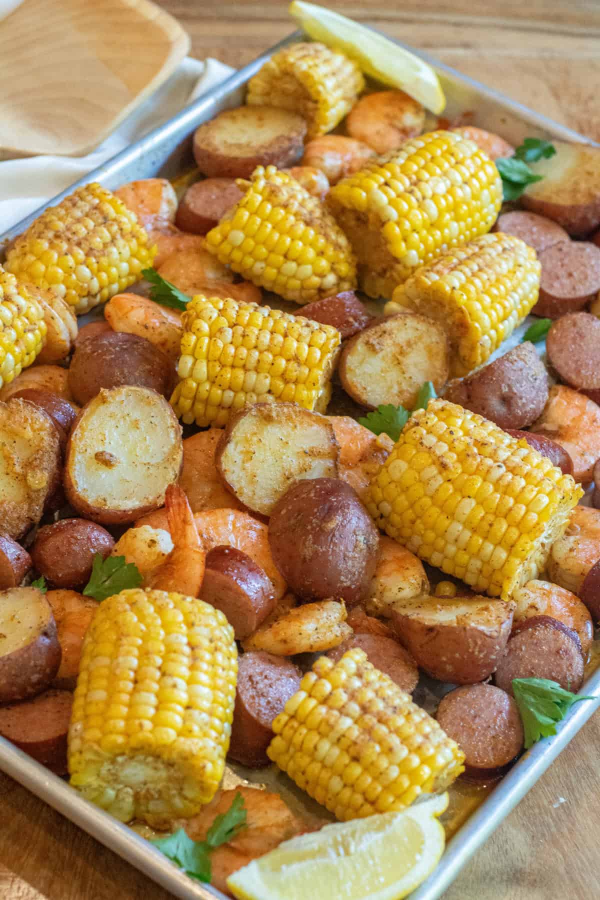 an overhead of a sheet pan with cooked corn on the cob pieces, shrimp, and potatoes.