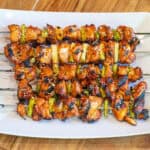 a plate with grilled chicken skewers with green onion and sesame seeds.