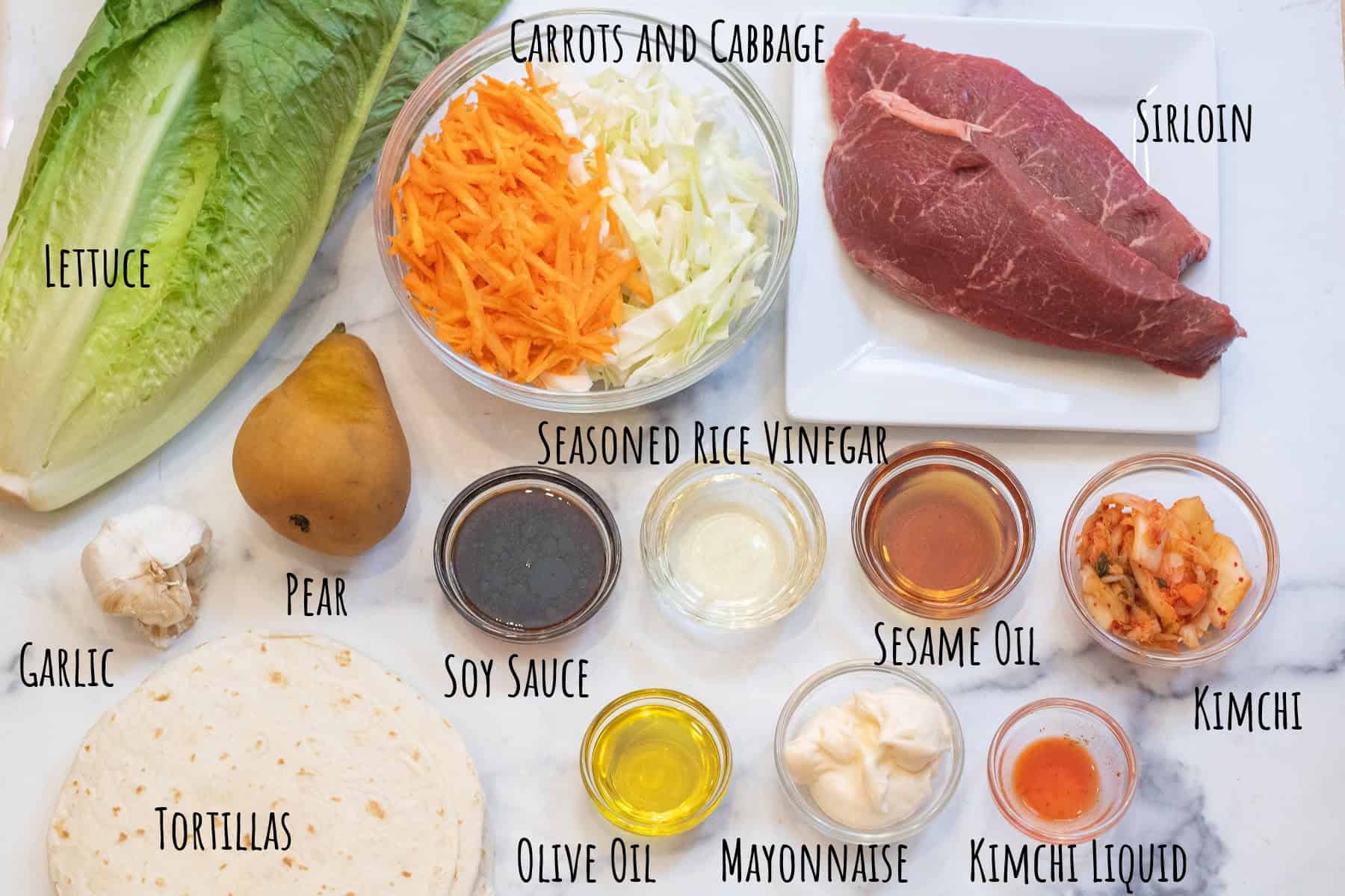 romaine lettuce, a bowl of shredded carrots, cabbage, sirloin steaks, a pear, and bowls of soy sauce, kimchi, sesame oil, vinegar, oil, mayo, and tortillas all labeled.