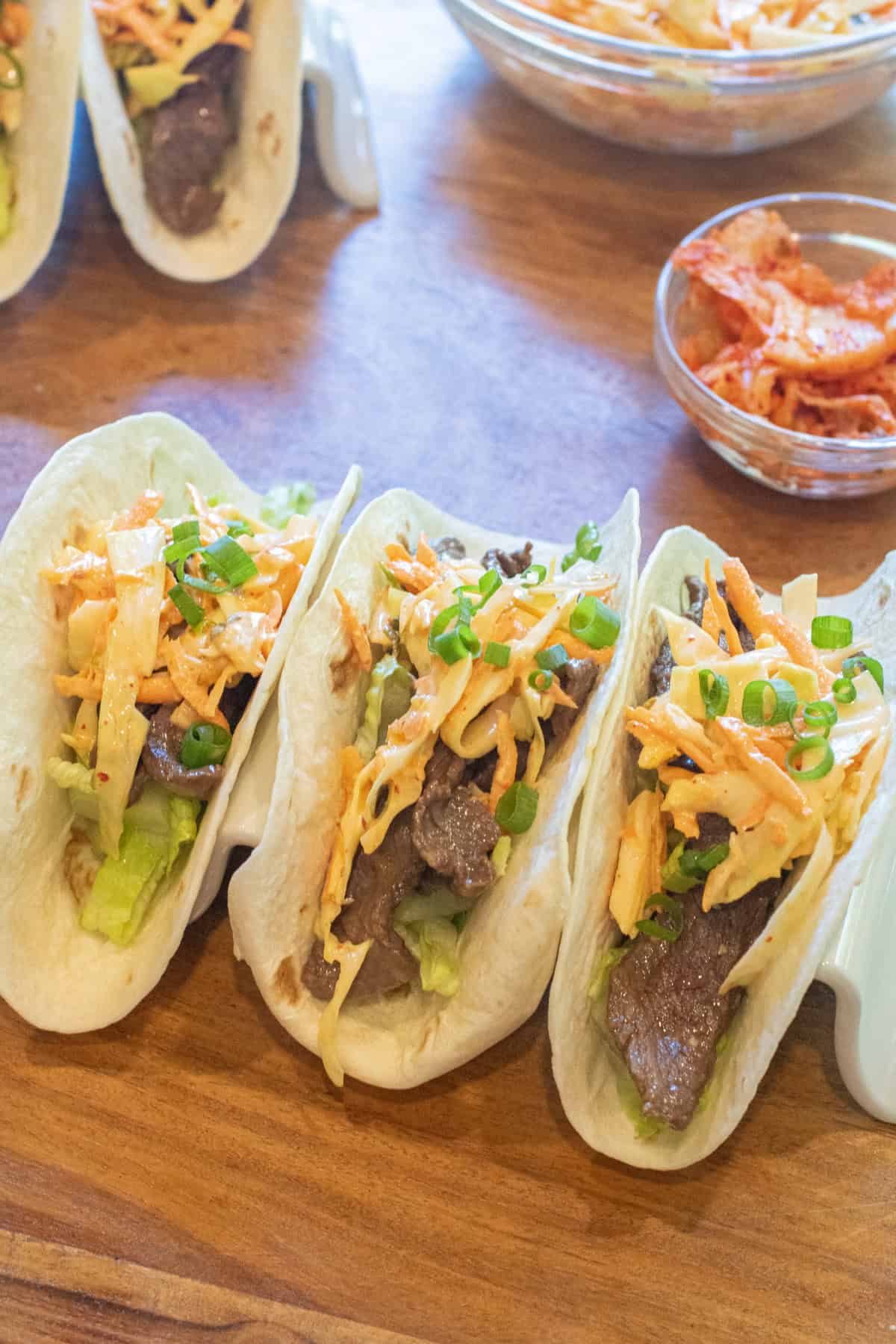 an overhead of 3 tacos in a taco holder with beef, slaw, and green onions on top.