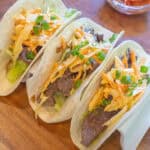 an overhead of 3 tacos in a taco holder with beef, slaw, and green onions on top.