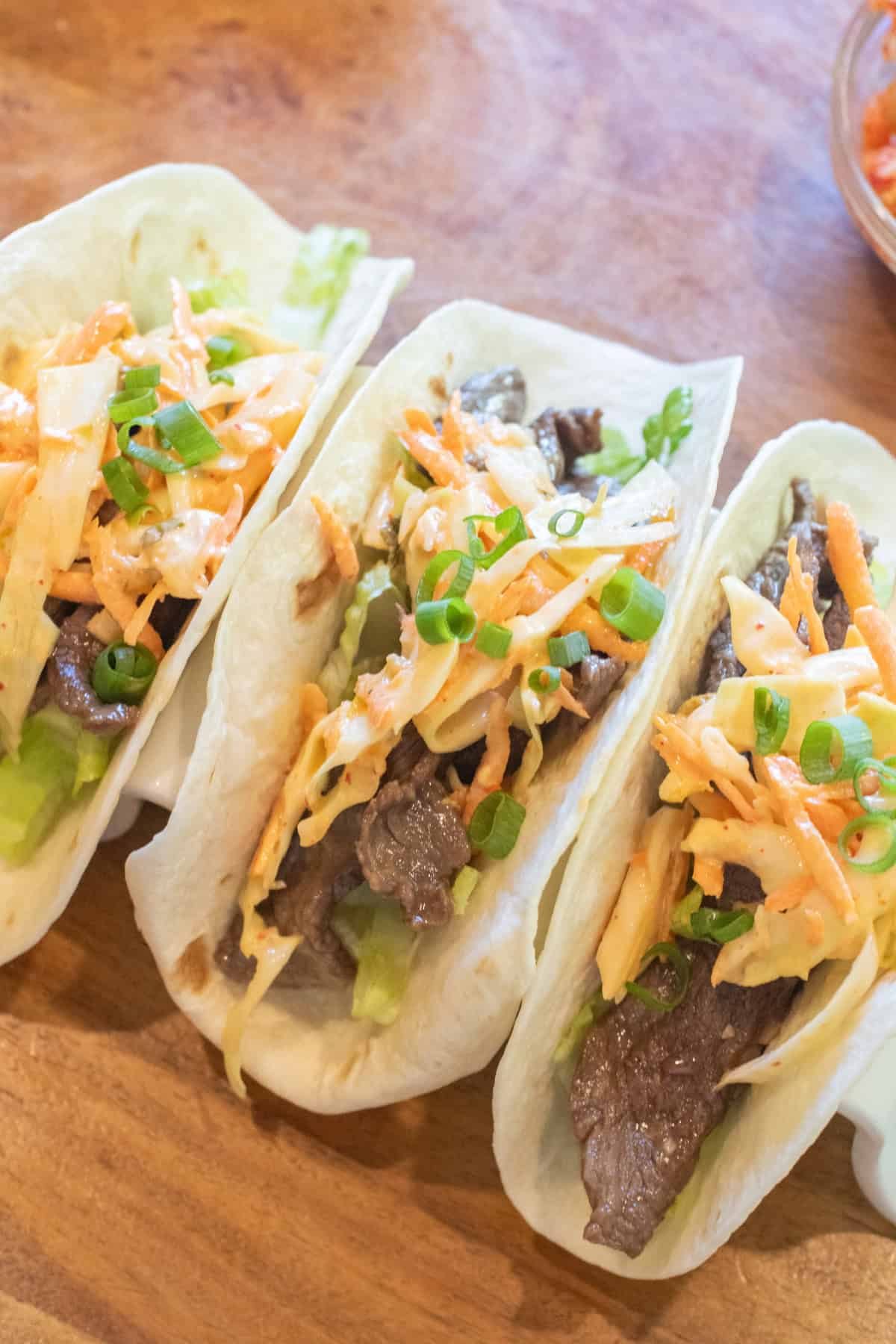 an overhead of 3 tacos in a taco holder with beef, slaw, and green onions on top.
