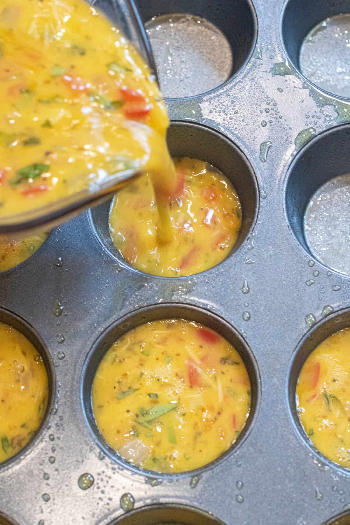 raw egg mixture being poured into a muffin tin.